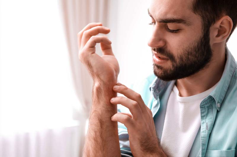 Man scratching his arm wondering if bee stings get worse each time